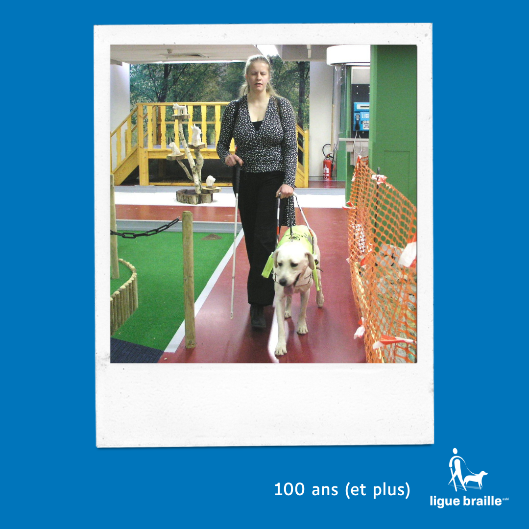 Photo d’une jeune femme aveugle qui teste le parcours du loco-local de la Ligue Braille avec une canne blanche et son chien guide. 